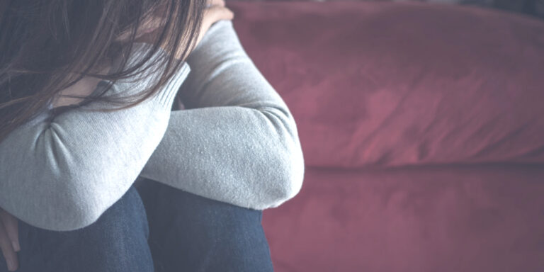Woman having moments of grief and sadness sitting on a couch