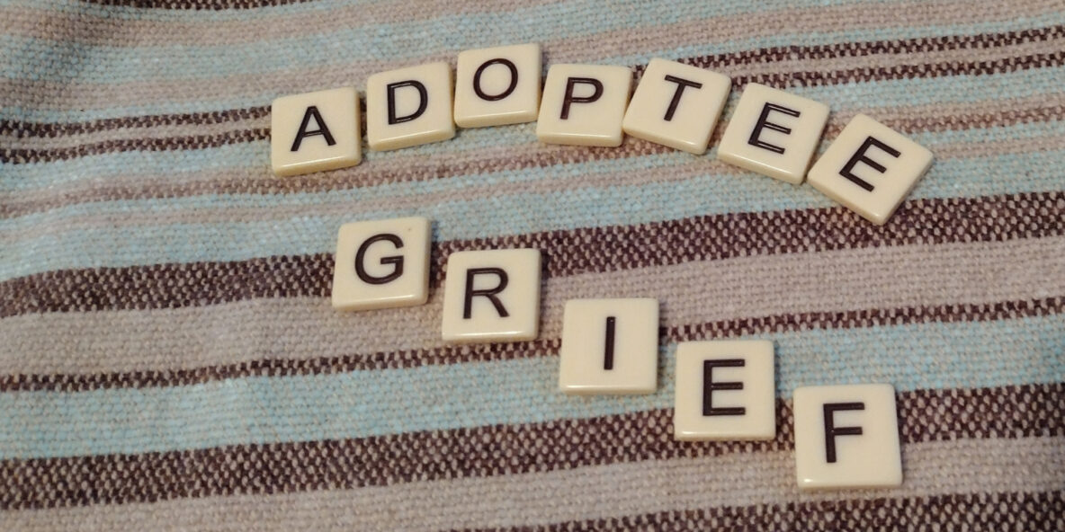 Tiles that spell out Adoptee grief on a background of brown and teal stripes