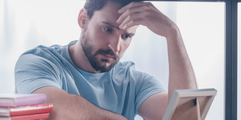 Sad man holding a picture, suggesting a grieving father