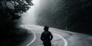 Black and white image of person standing on a lonely road